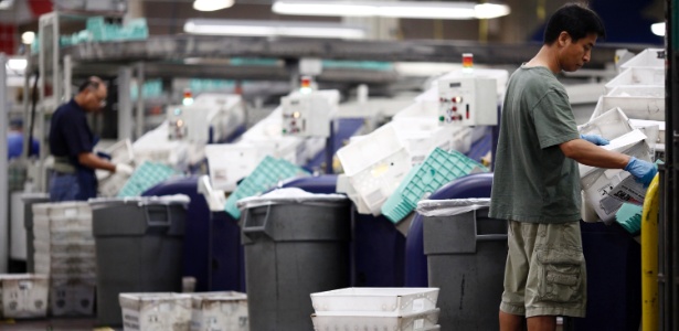 Homens trabalham no Centro de Processamento e Distribuição do Serviço Postal - Luke Sharrett/The New York Times