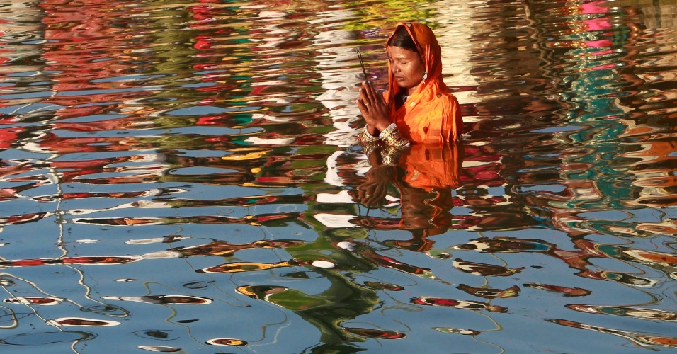 29.out.2014 - Mulher adora o deus Sol Surya nas águas do lago Laxmi Narayan durante o festival religioso hindu de Chatt Puja na cidade de Agartala, na Índia
