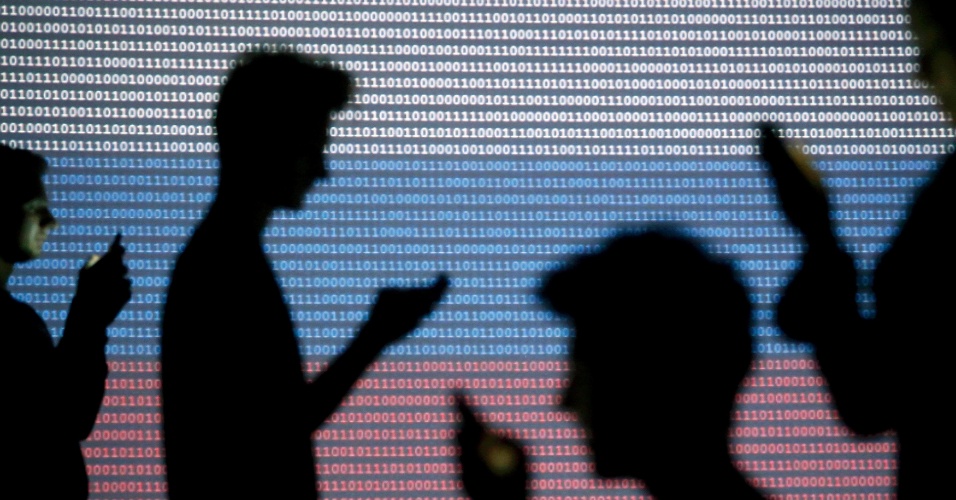 29.out.2014 - Pessoas com dispositivos móveis passam em frente de uma tela projetada com um código binário e uma bandeira nacional russa, em Zenica, na Bósnia