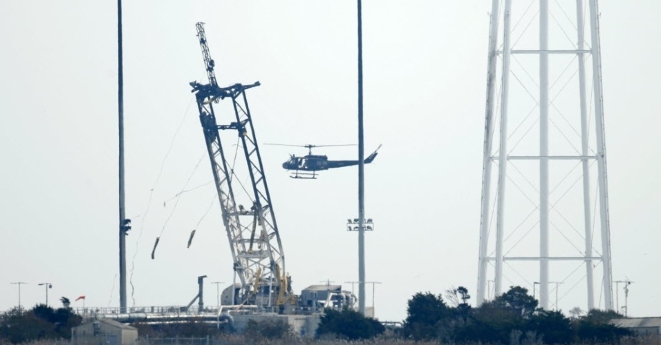 29.out.2014 - Um helicóptero faz o reconhecimento da área da plataforma de lançamento da Nasa na Ilha Wallops, na Virgínia (EUA). As autoridades começaram a investigar a causa da explosão do foguete Antares, da empresa privada americana Orbital Sciences Corporation