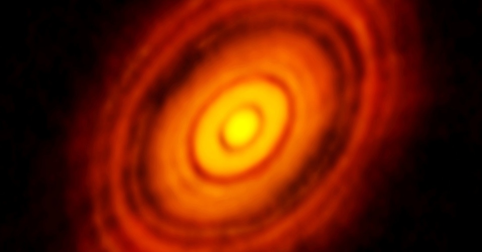 7.nov.2014 - HL Tauri, estrela anã laranja a 450 anos-luz de distância, localizada na constelação de Touro. Os astrônomos, que sempre escolhem cuidadosamente suas palavras, veem ali, pela primeira vez com esse nível de clareza, algo singelo: uma série de vãos bem delineados no disco de gás e poeira que envolve a estrela jovem. Delineados, com toda probabilidade, por planetas recém-nascidos que estão varrendo a região de suas órbitas, acumulando matéria até atingirem seu tamanho final. Neste exato momento, em torno de uma jovem estrela apenas ligeiramente menor que o Sol, nasce um novo sistema planetário na Via Láctea