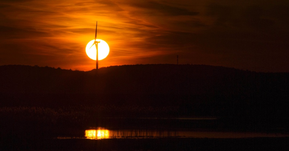 11.nov.2014 - O sol se põe atrás de uma turbina eólica nas salinas do Refúgio Nacional da Vida Selvagem Parker, em Plum Island, em Massachusetts (EUA)