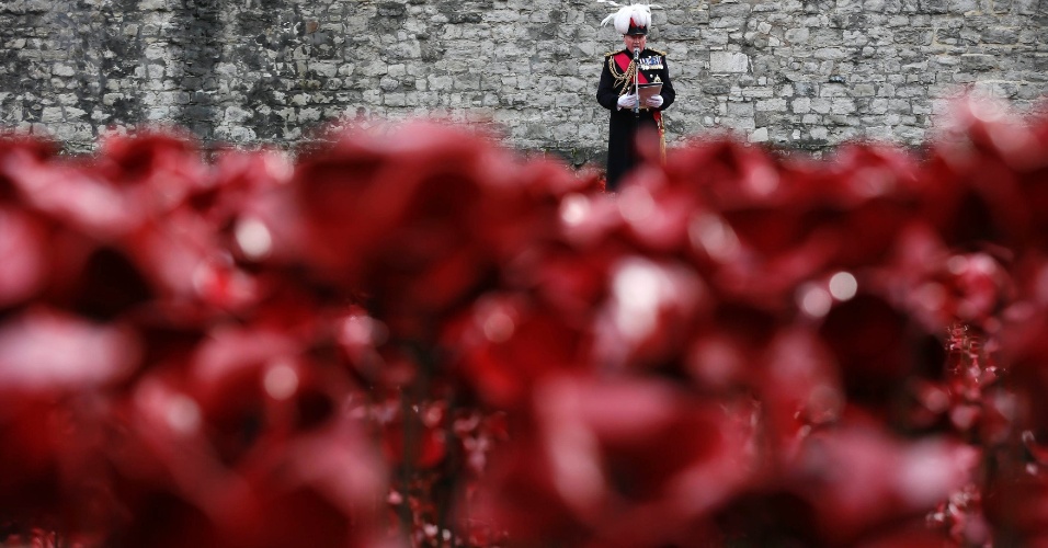 11.nov.2014 - Oficial do Exército britânico, entre papoulas de cerâmica, que fazem parte da instalação de arte "Blood Swept terras e mares de Vermelho", durante cerimônia no Dia do Armistício na Torre de Londres, no Reino Unido