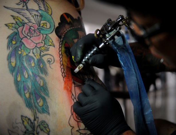 Tatuador trabalha em uma cliente: cuidados com agulha e pigmentação - Sonny Tumbelaka/AFP