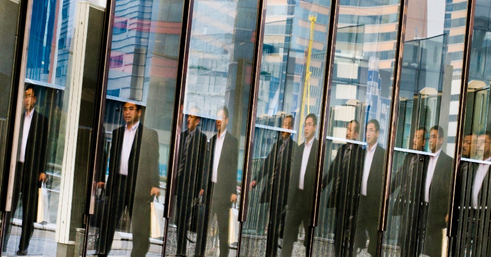 17.nov.2014 - Reflexo de um homem aparece repetidas vezes em uma grade de vidro no distrito de negócios Shiodome em Tóquio, no Japão