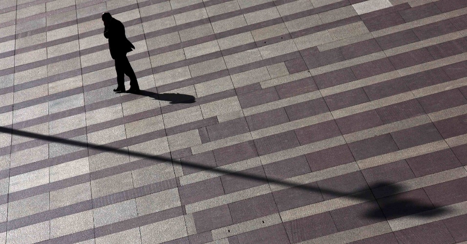 17.nov.2014 - Homem fala no celular enquanto caminha sobre um piso estampado no pátio fora de um prédio de escritórios no distrito financeiro de Madrid, na Espanha