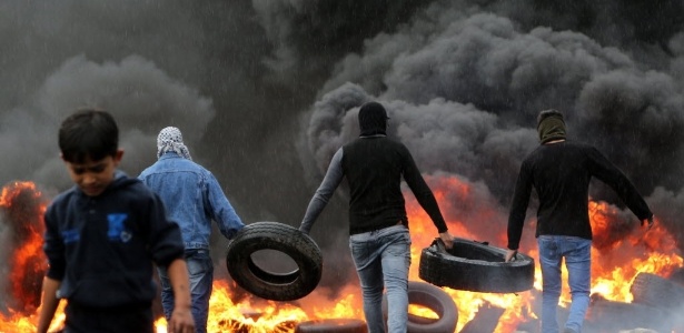 Palestinos fazem barricada com pneus queimados durante confrontos contra forças israelenses - Jaafar Ashtiyeh/AFP