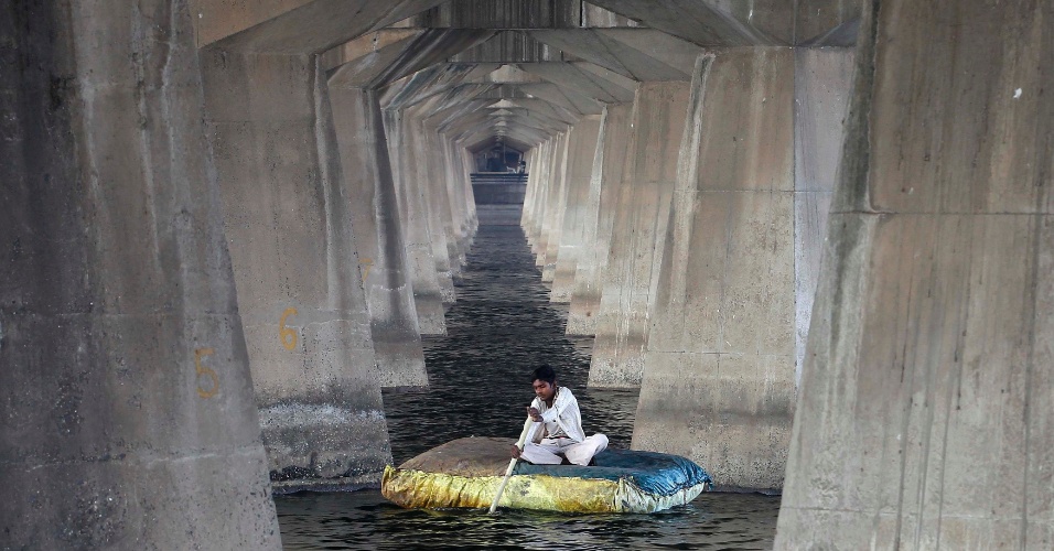 25.nov.2014 - Um pescador navegou nesta terça-feira (25) em uma balsa sob ponte no rio Sabarmati, na cidade de Ahmedabad, na Índia