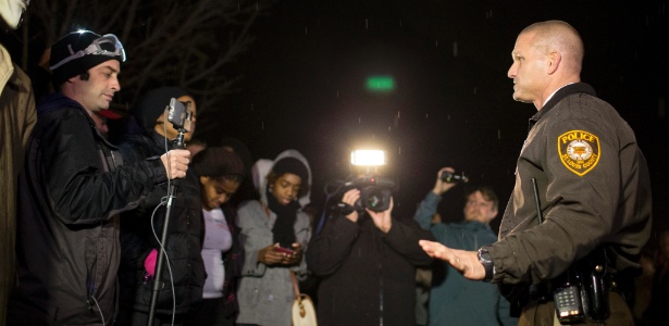 O tenente  da polícia do condado de Saint Louis, Jerry Lohr, conversa com manifestantes e jornalistas em frente à delagacia em Ferguson, no sábado (22) - Whitney Curtis/The New York Times