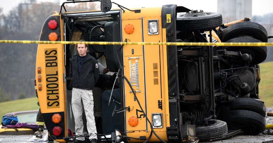 3.dez.2014 - Um homem ficou ao lado de ônibus escolar que tombou após batida com outro coletivo nesta terça-feira (2) na cidade de Knoxville, no Tennessee, nos Estados Unidos. O acidente matou duas crianças e um adulto, e deixou 23 pessoas feridas