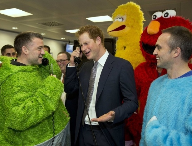 3.dez.2014 - O príncipe Harry (ao centro) falou em um telefone nesta quarta-feira (3) durante um evento de caridade ao lado de pessoas vestidas como os personagens do seriado Vila Sésamo no centro de Londres, na Inglaterra