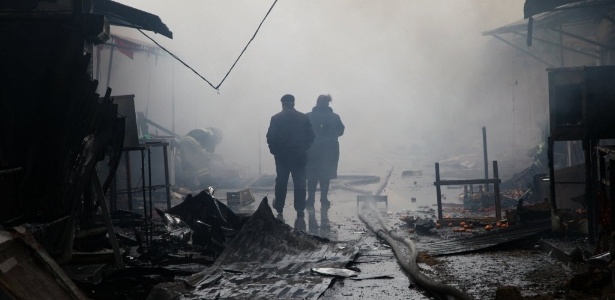 Dois homens analisaram os estragos em um quiosque de um mercado queimado, ao lado de um edifício da empresa de mídia local chamada Casa da Imprensa que foi incendiado nesta quinta-feira (4), no centro de Grozni - Elena Fitkulina/ AFP