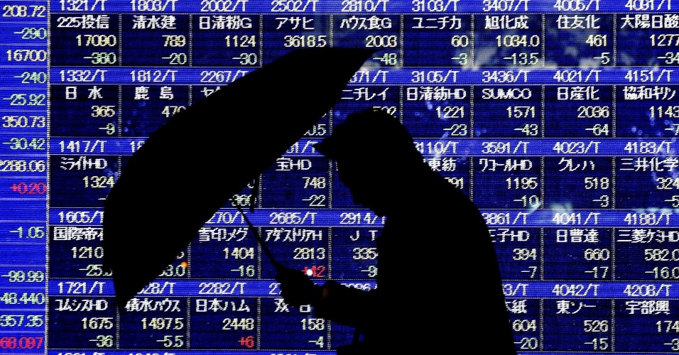 16.dez.2014 - Um homem passa por um painel eletrônico mostrando os preços das ações em Tóquio, no Japão
