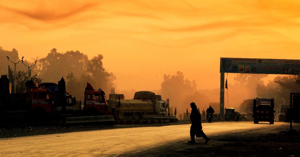 19.dez.2014 - Homem atravessa a rua em meio a céu alaranjado durante o amanhecer, perto da base militar de Fenty, no Afeganistão