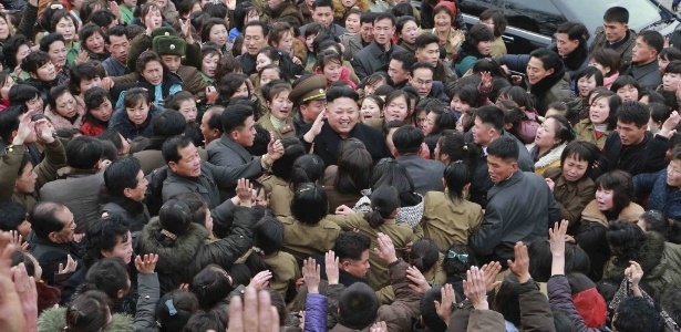O ditador norte-coreano Kim Jong-un sorri enquanto uma multidão o rodeia durante visita a uma fábrica têxtil em Pyongyang - KCNA/Reuters