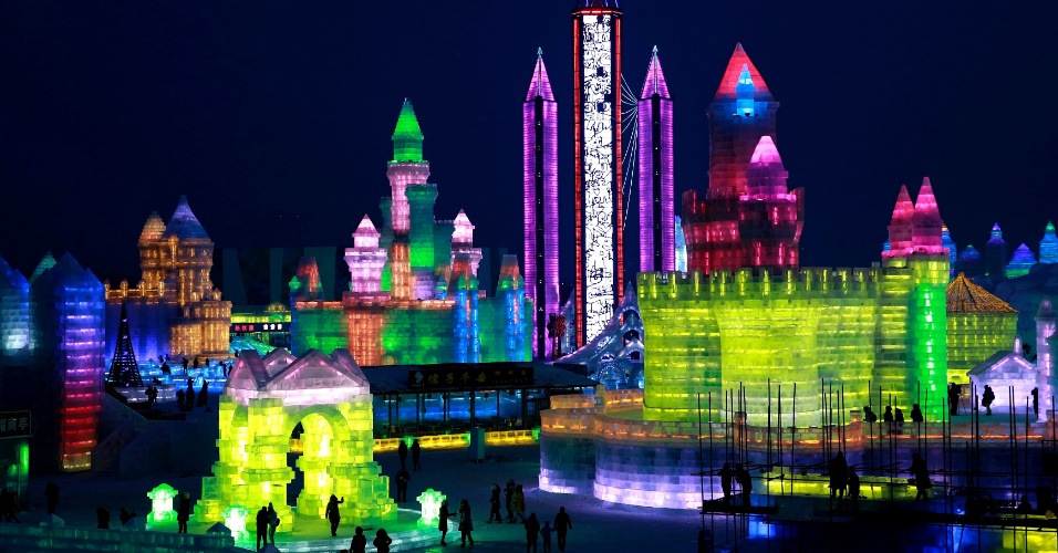 23.dez.2014 - Chineses caminham perto de esculturas de gelo iluminadas com luzes coloridas durante a noite de testes do Festival da Neve e do Gelo de Harbin, na província Heilongjiang, na China