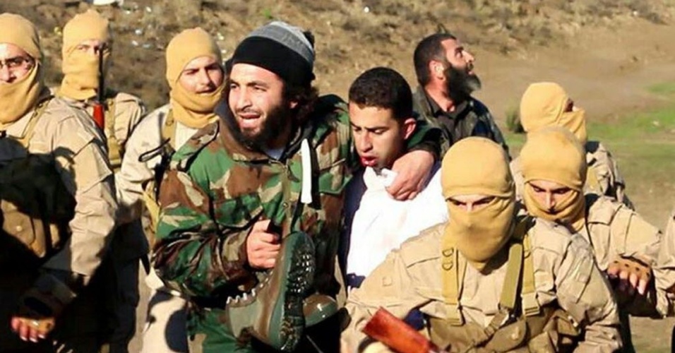 24.dez.2014 - Imagem divulgada pelo grupo Estado Islâmico (EI) em sites jihadistas mostram supostamente um piloto Jordanian (de roupa branca) capturado pelos combatentes que teriam derrubado um avião militar da coalizão internacional na cidade de Al Raqqah, na Síria