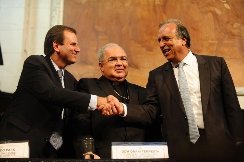 1º.jan.2015 - O governador do Rio de Janeiro, Luiz Fernando Pezão (PMDB), cumprimenta o prefeito do Rio, Eduardo Paes (PMDB), com o cardeal Dom Orani Tempesta entre eles