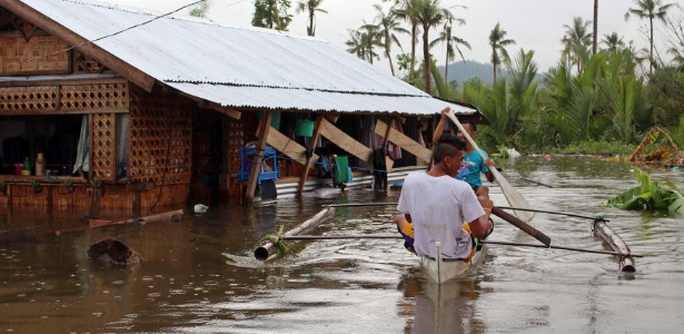 30.dez.2014 - Moradores usam barco para deixar suas casas atingidas por inundação provocada pela passagem da tempestade tropical Jangmi, em Seniang, na província de Samar, nas Filipinas - Rowel Montes/ Reuters