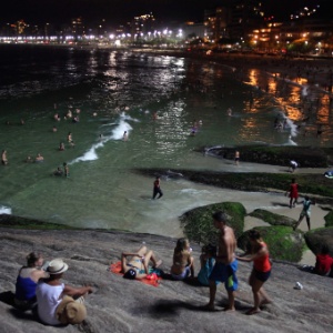 Na noite deste sábado (3), a praia do Arpoador, no Rio, ficou cheia de banhistas - Marcelo Sayão/Efe