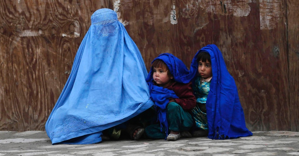 22.jan.2015 - Mulher espera por transporte com seus filhos em um dia frio, em Cabul, no Afeganistão