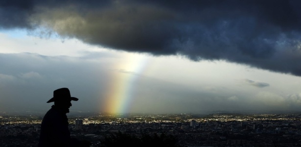 Homem observa um arco-íris que sai de uma grande massa de nuvens carregadas em San José, na Costa Rica - Juan Carlos Ulate/Reuters