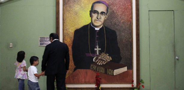 26.out.2014 - Pessoas passam por retrato de Oscar Romero na catedral de San Salvador; o arcebispo foi declarado mártir pelo papa Francisco