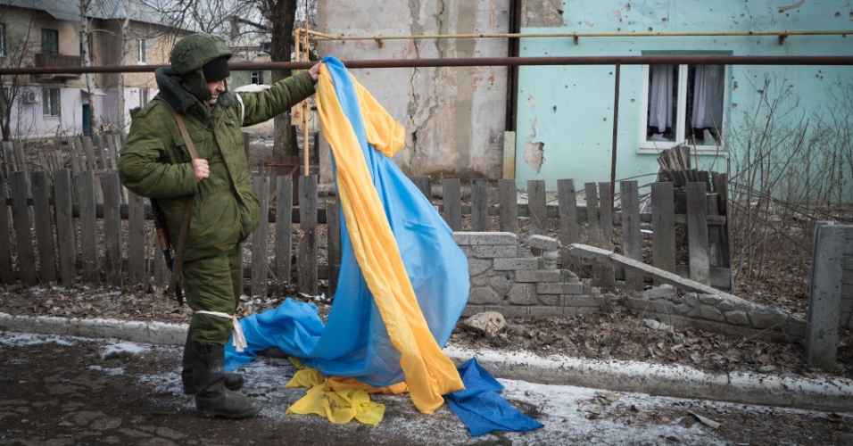 7.fev.2015 - Um rebelde pró-Rússia recolhe bandeira ucrânia em rua de Vuglegirsk, na região de Donetsk, no leste da Ucrânia. As autoridades ucranianas afirmaram que há razões para ser otimista sobre um acordo de paz com a Ucrânia, mas também alertou contra iniciativas para armar o exército de Kiev, e culpou os Estados Unidos e a Europa por 