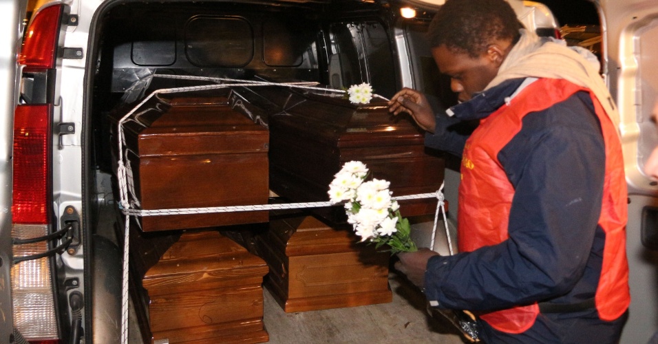 12.fev.2015 - Homem deposita flores sobre caixões de imigrantes que morreram ao tentar chegar na costa italiana, em Porto Empedocle, na região da Sicília, onde os mortos serão enterrados