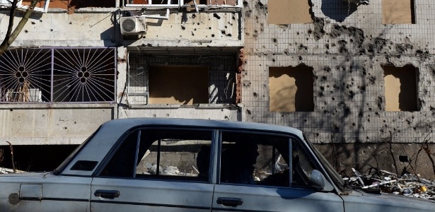 Motorista passa por prédio destruído por bombardeio em Donetsk, no leste da Ucrânia - Vasily Maximov/AFP