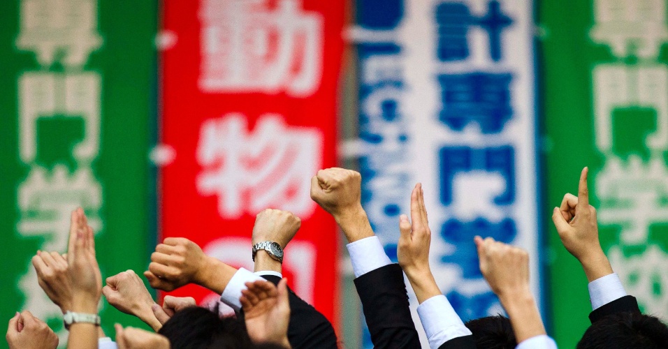 20.fev.2015 - Estudantes universitários levantam as mãos em uma demonstração de auto-encorajamento, durante evento para procurar emprego em um teatro ao ar livre, em Tóquio, no Japão