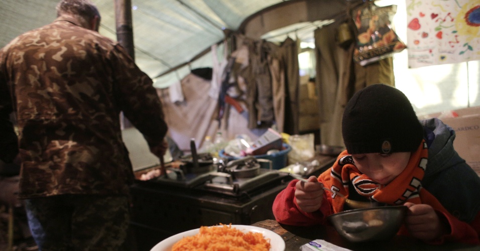 23.fev.2015 - Um soldado ucraniano alimenta um menino em um posto de controle perto Horlivka, na região de Donetsk. As forças pró-Rússia se concentraram nas proximidades da cidade portuária da Ucrânia de Mariupol e continuam a atacar posições de tropas do governo ucraniano, alimentando preocupações com o destino de um cessar-fogo mediado internacionalmente
