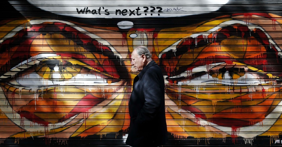 25.fev.2015 - Um homem caminha junto a grafite, em Atenas, na Grécia