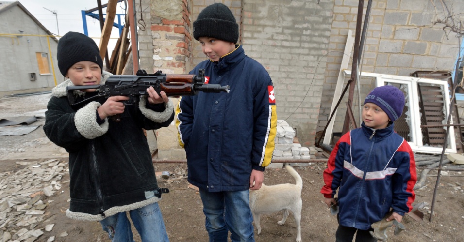26.fev.2015 - Crianças brincam com uma submetralhadora dada por soldados ucranianos no vilarejo de Chermalyk, a 40 quilômetros do porto de Mariupol, no leste do país