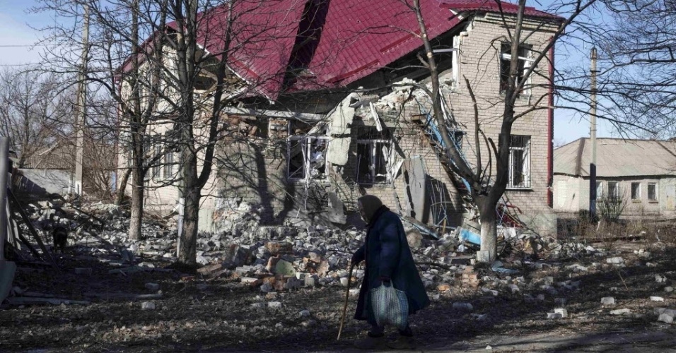 28.fev.2015 - Idosa caminha na frente de uma casa na cidade de Debaltseve, na Ucrânia, destruída pelo conflito entre o Exército nacional e rebeldes separatistas pró-Rússia. A cidade está sob domínio dos rebeldes