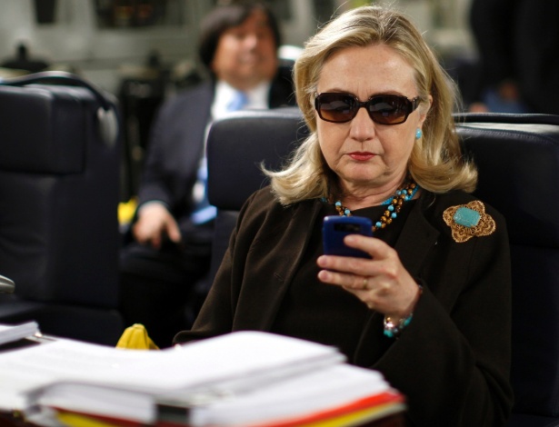 Nesta foto de 18 de outubro de 2011, a então secretária de Estado dos EUA, Hillary Clinton, checa seu celular a bordo de aeronave militar com direção à Líbia - Kevin Lamarque/Reuters