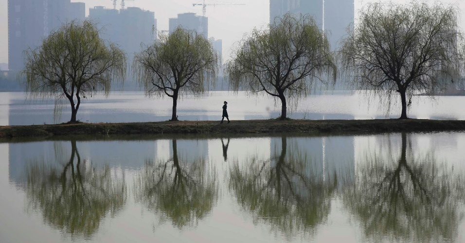 6.mar.2015 - Mulher caminha próximo a um canteiro de obras de um complexo residencial em Wuhan, província de Hubei, na China