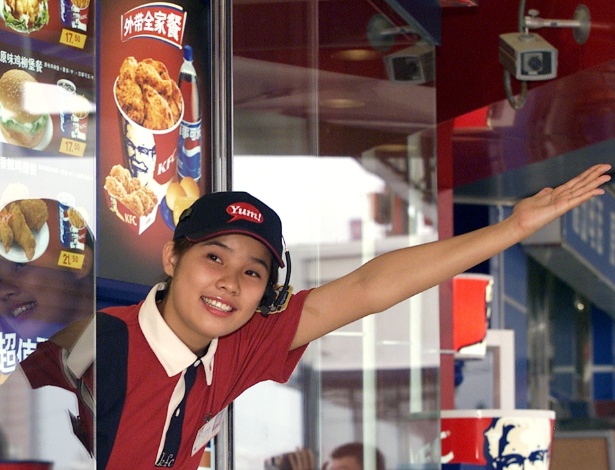 Funcionária da loja KFC (Kentucky Fried Chicken) dá as boas-vindas a consumidor em unidade drive-thru de Pequim, na China. O consumo ampliado de fast food é apontado como uma das causas no aumento de doenças cardiovasculares no país - Wilson Chu/Reuters