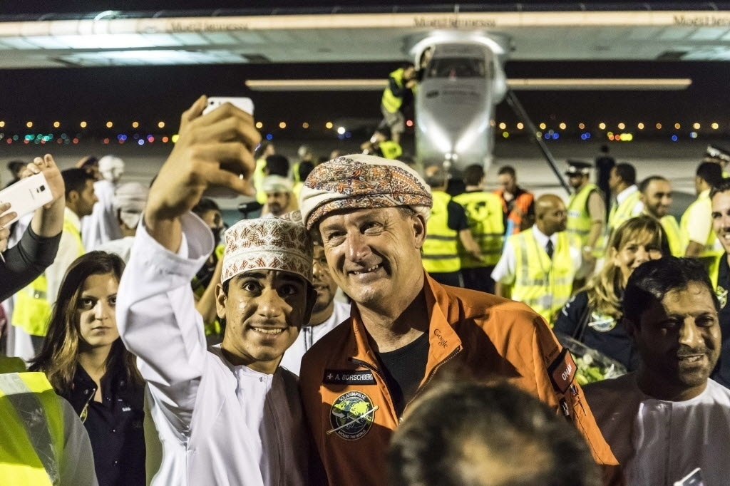 9.mar.2015 - O piloto Andre Boschberg (c) posa para uma foto com um homem após desembarcar em Mascate em direção a Ahmedabad, no oeste da Índia. Os pilotos suíços Bertrand Piccard e Andre Borschberg tentam o primeiro voo ao redor do mundo em um avião movido a energia solar. - Jean Revillard/Reuters