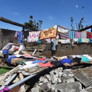 Mulher estende roupa em escombros de casa destruída pela passagem do ciclone Pam por Porto Vila - Dave Hunt/ EFE