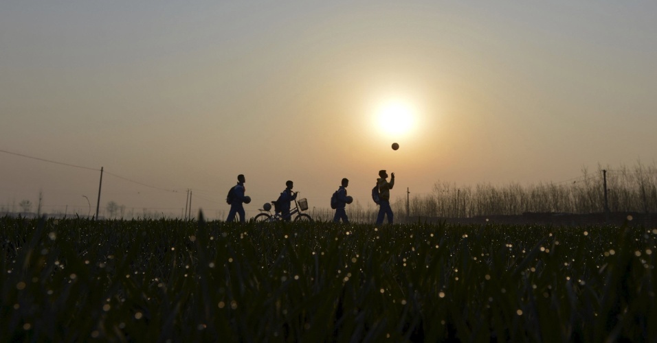 27.mar.2015 - Alunos brincam com bolas de futebol durante seu trajeto até o Centro de Ensino Fundamental Sunji, na província de Shandong, na China