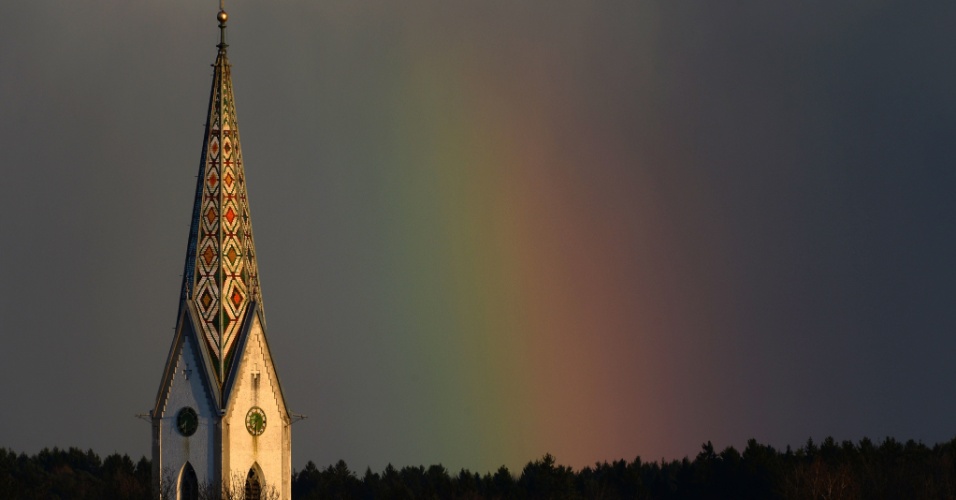 1º.abr.2015 - Um arco-íris pode ser visto em um céu cinzento atrás do campanário da Oberteuringen, na Alemanha