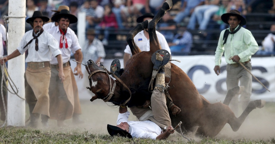 01.abr.2015 - Peão cai de cavalo selvagem durante montaria em celebração da Semana Criolla em Montevidéo, no Uruguai