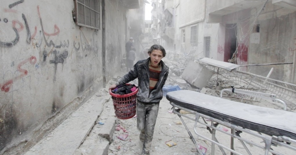 2.abr.2015 - Menino carrega seus pertences de local atingido por uma bomba, que foi lançada pelas forças leais ao ditador sírio Bashar al Assad, no distrito de al-Fardous de Aleppo