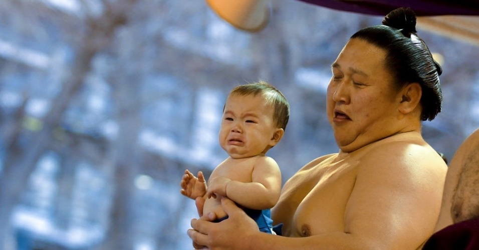 3.abr.2015 - Um lutador de sumô carrega um bebê antes de um torneio no santuário Yasukuni, em Tóquio, no Japão