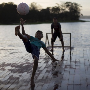 Garotos jogam futebol em cima de plataforma de madeira sobre o rio Negro, na comunidade ribeirinha de Catalão, perto de Manaus - Bruno Kelly/Reuters