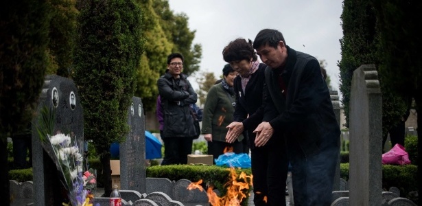 Casal oferece orações enquanto queimam dinheiro durante o festival anual "Qingming", conhecido como "Dia de Varrrer a Sepultura", em um cemitério de Xangai, na China - Johannes Eisele/AFP 