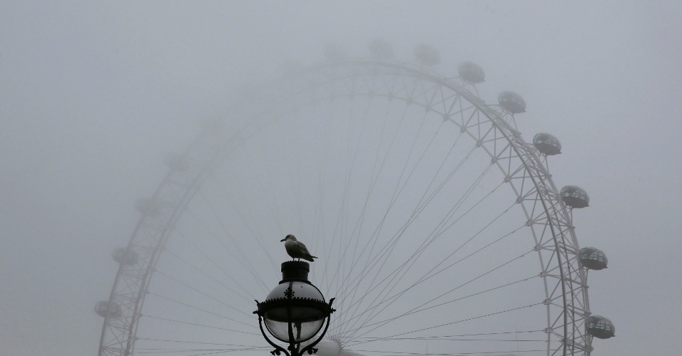9.abr.2015 - Pássaro pousa em uma lâmpada de rua em frente a London Eye (roda gigante) em uma manhã de nevoeiro no centro de Londres, na Inglaterra