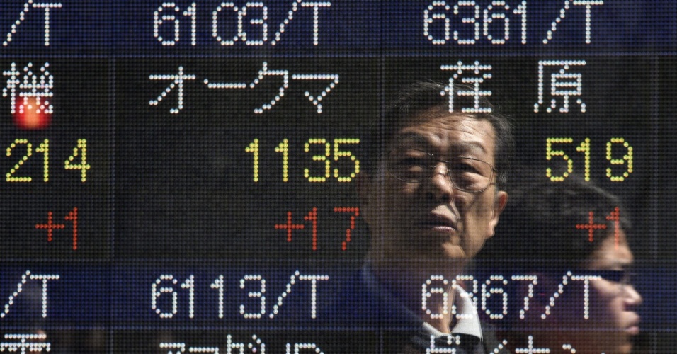9.abr.2015 - Imagem de homem é refletida em um painel eletrônico de informações com dados da bolsa em Tóquio, no Japão