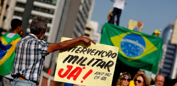 12.abr.2015 - Manifestante segura cartaz com os dizeres "Intervenção militar já!" durante protesto na avenida Paulista, em São Paulo